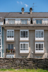 facade of a block of flats with its roof, its windows in each home and its chimneys and antennae