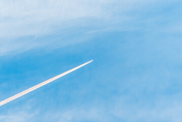 An airplane and a white trail from an airplane in a blue summer sky.airplane flying through blue sky with long vapor trails.Copy space.