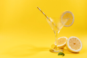 empty lemonade glass with lemon on yellow background