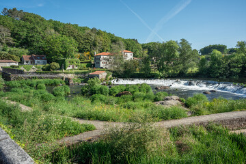 Fototapeta na wymiar village of Ponte Maceira, La Coruña, in Spain. With old houses among the trees of the forest and with a river full of vegetation and rocks surrounded by a small waterfall in the field