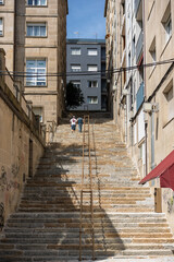 long staircases between urban buildings with a couple of people walking up them 