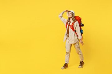 Full body fun young woman carry bag with stuff mat look far away distance isolated on plain yellow background. Tourist leads active lifestyle walk on spare time. Hiking trek rest travel trip concept.