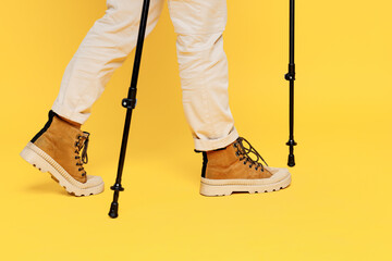 Plakat Cropped close up side view woman wear sporty shoes hold trekking poles go isolated on plain yellow background. Tourist leads active lifestyle walk on spare time. Hiking trek rest travel trip concept.