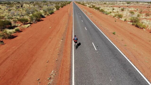 Man riding bike on Outback Australian Desert road