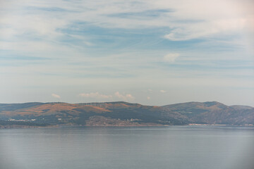 image taken with a telephoto lens of the coast of Galicia, Spain, with its mountains and windmills in the distance, on a day with cloudy sky