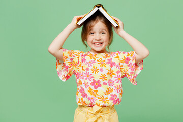 Little shocked amazed child kid girl 6-7 years old wear casual clothes have fun read hold book above head isolated on plain pastel green background studio Mother's Day love family lifestyle concept.