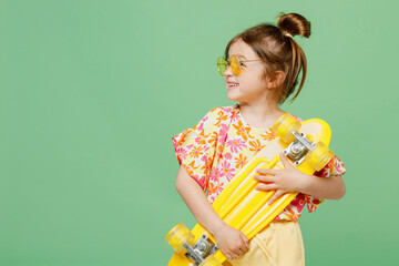 Little cute child kid girl 6-7 years old wear casual clothes have fun hod in hand skateboard look aside on area isolated on plain pastel green background. Mother's Day love family lifestyle concept. - obrazy, fototapety, plakaty