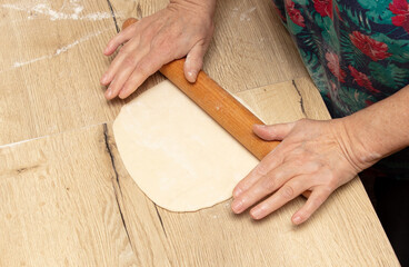 Close-up of an elderly woman rolling dough with a rolling pin