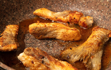 The fish is fried in a frying pan in oil. Close-up.