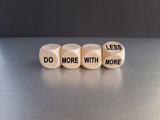Wooden cubes form the expression 'do more with less'. Beautiful grey table, black background. Copy...