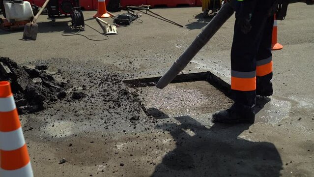 Worker with air compressor tool cleans asphalt