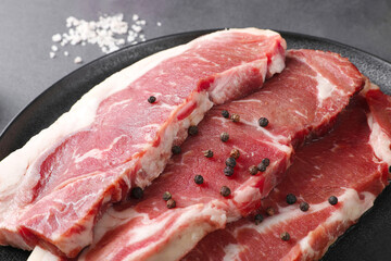 Beef served in black cutlery, indoors, dark background, top view