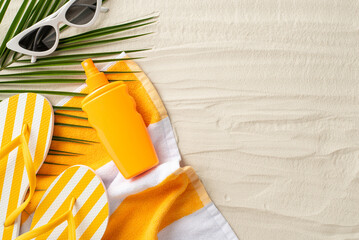 Fototapeta na wymiar Healthy suntan concept. High angle view photo of sunscreen spray,sunglasses, slippers and palm leaf on a beach towel on isolated sand background with copyspace