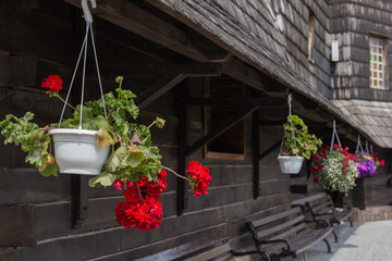 Flowerpots with geranium suspended under of wooden church roof outdoors