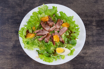 Salad with boiled duck meat, egg, orange, greens, top view