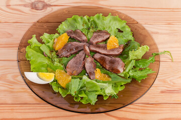 Salad of duck meat with different greens on glass dish