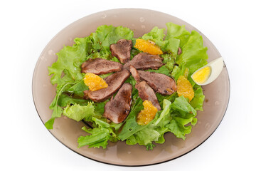 Salad of duck meat with different greens on glass dish