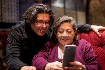 grandson and grandmother chatting on her smartphone having fun