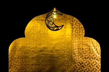 Decorated moon shape light hanging on top of black paper cut in mosque shape with golden paper background for Islamic new year concept.