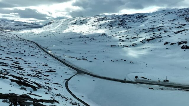 Strynefjellet Mountain Road RV 15 in Breiddalen valley at sunny spring day with still snow left in the hills - Aerial showing intersection with old road FV 63 to Geiranger - Aerial