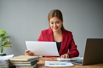 An Asian businesswoman using a calculator to plan budgets and working on financial reports