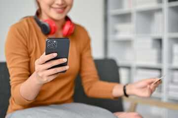 Close-up image of a beautiful Asian woman using her smartphone to pay her online bills