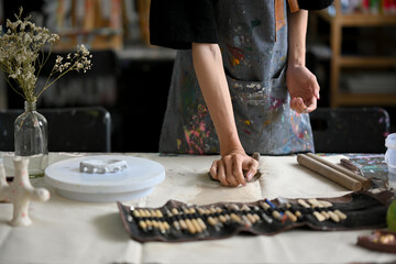 Close-up image of a male artist potter kneading raw clay at his worktable in his pottery studio.