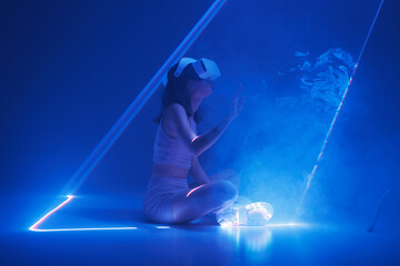 Woman with futuristic tablet in hand. Girl in glasses of virtual reality presses the start button. Augmented reality game, future technology, AI concept. Holographic interface to display data.