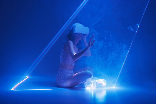 Woman with futuristic tablet in hand. Girl in glasses of virtual reality presses the start button. Augmented reality game, future technology, AI concept. Holographic interface to display data.