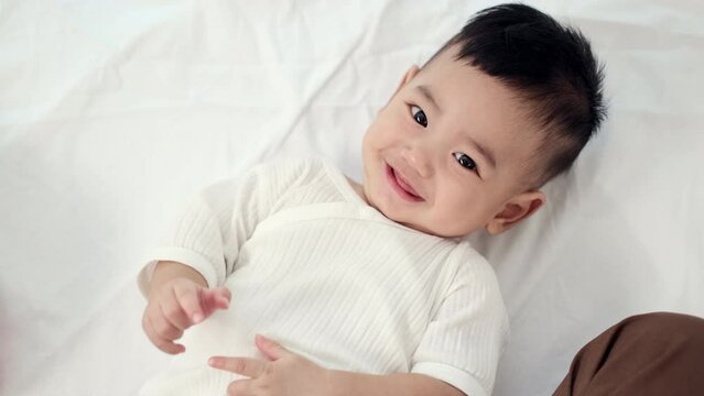 Good mood Adorable asian baby comfortable, Lying on a bed looking at camera. Baby healthcare hygiene concept.