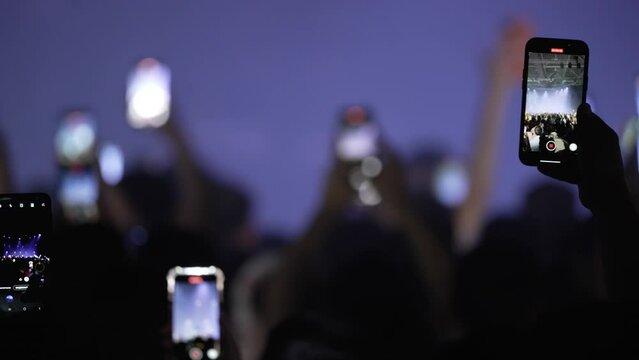 At the concert, people hold smartphones in front of the stage, broadcast live, record videos and take pictures.
