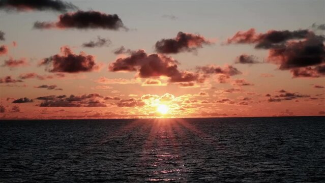 Beautiful sunrise with solar flares over the ocean as seen from a moving boat