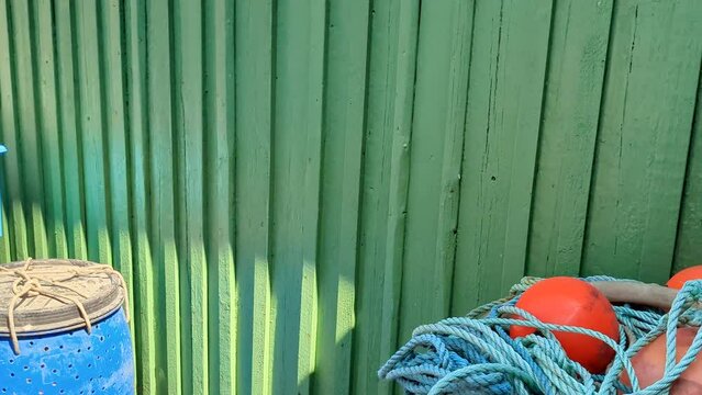 4K 60FPS Blue Plastic Drums Used as Well Boxes and Fishing Marker Flags Stored Harbor Next to Fishing Sheds - Panning Shot