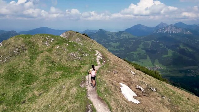 Young woman hiking on a mountain ridge with spectacular view