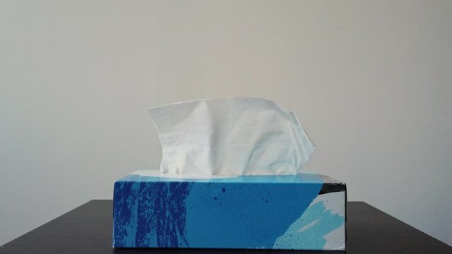 Slow motion shot of a male hand grabbing a tissue from a box standing on a nightstand
