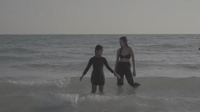 Family mother and daughter run jumping  at sea bleach