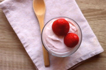Bowl of strawberry yogurt with two fresh strawberries on the top. Flat lay.