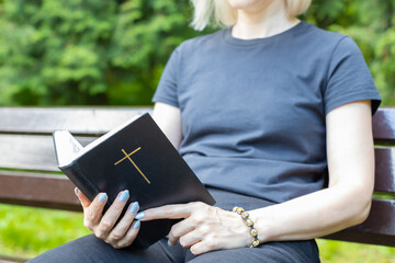 woman reading the bible sitting on a bench.