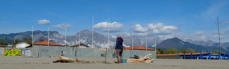 Spiaggia Libera La Rotonda bei Carrara in Italien mit Mann wo Baum sägt