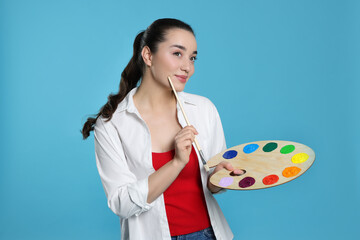 Woman with painting tools on light blue background. Young artist