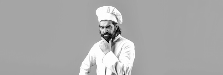 Naklejka premium Cook hat. Serious cook in white uniform, chef hat. Portrait of a serious chef cook. Black and white