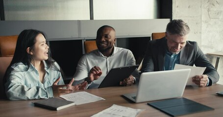 A multiracial company is discussing a new assignment. Solving problems in a professional setting for a successful trio