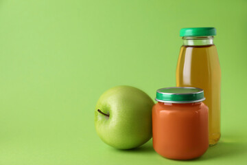 Healthy baby food, juice and apple on green background, space for text