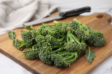 Fresh raw broccolini on wooden board, closeup. Healthy food