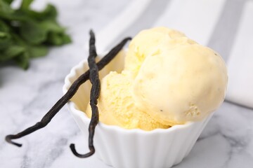 Delicious ice cream and vanilla pods on white marble table, closeup