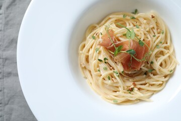 Tasty spaghetti with prosciutto and microgreens on plate, top view. Exquisite presentation of pasta dish
