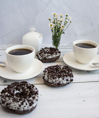 Chocolate donuts with cup of coffee. on white wooden table.