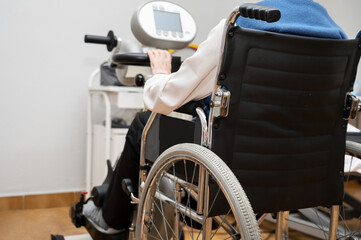 Fototapeta premium An unrecognizable elderly woman does pedal exercises from wheel chair at hospital. High quality photo.