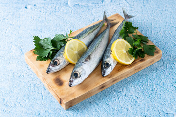 Raw mackerel fish on cutting board and blue background