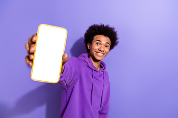 Portrait of cheerful person with stylish hairstyle wear violet hoodie show you smartphone touchscreen isolated on purple color background